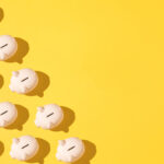 Little pink ceramic piggy bank pattern on the left side on yellow background. Concept of saving money, savings.