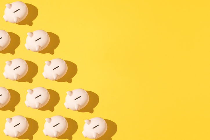 Little pink ceramic piggy bank pattern on the left side on yellow background. Concept of saving money, savings.